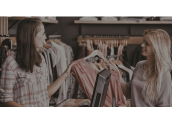Retail sales associate helping woman in clothing store