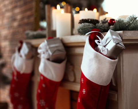 Decorative fireplace with Christmas stocking and gifts in stylish room interior