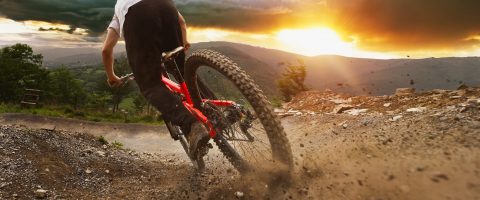 Man on mountain bike rides on the trail on a stormy sunset.