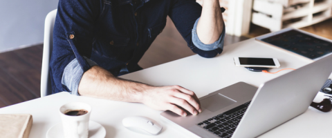 Man working on computer while eating breakfast.